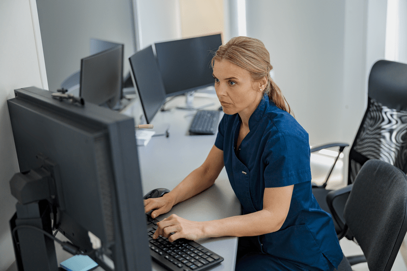 Nurse on Duty working on computer at the Reception Desk in modern clinic. High quality photo