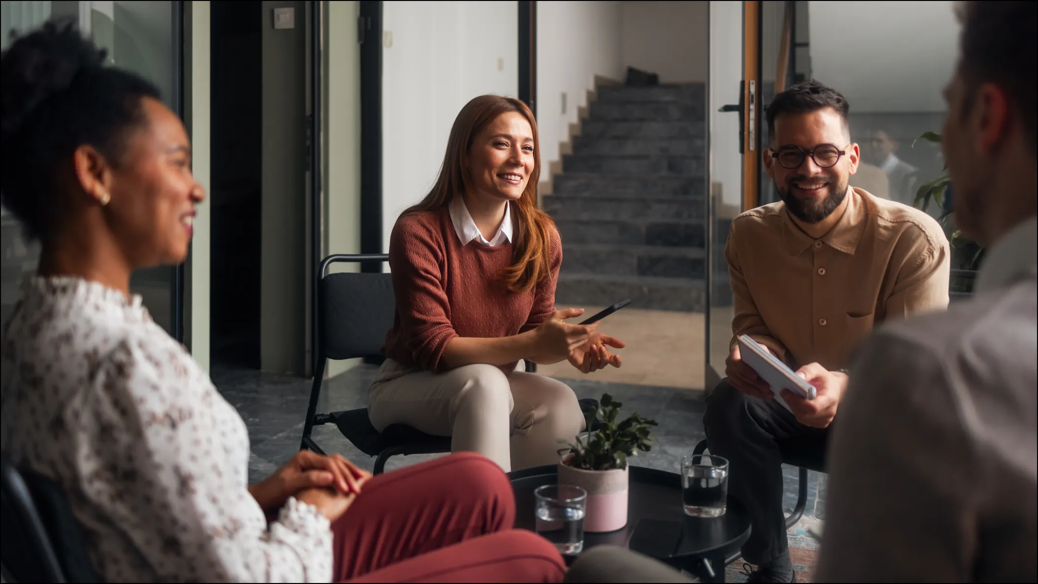 A young female professional chats to two male colleagues in an informal setting