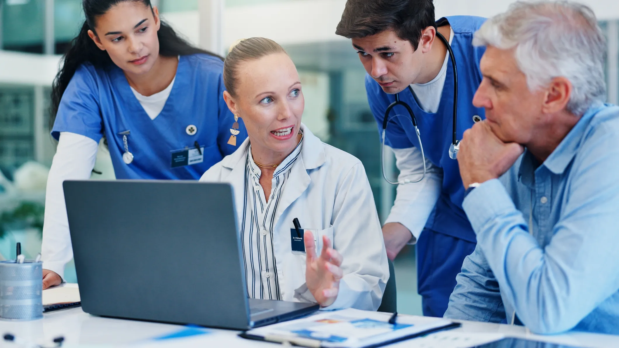Woman, doctors and laptop with group at hospital