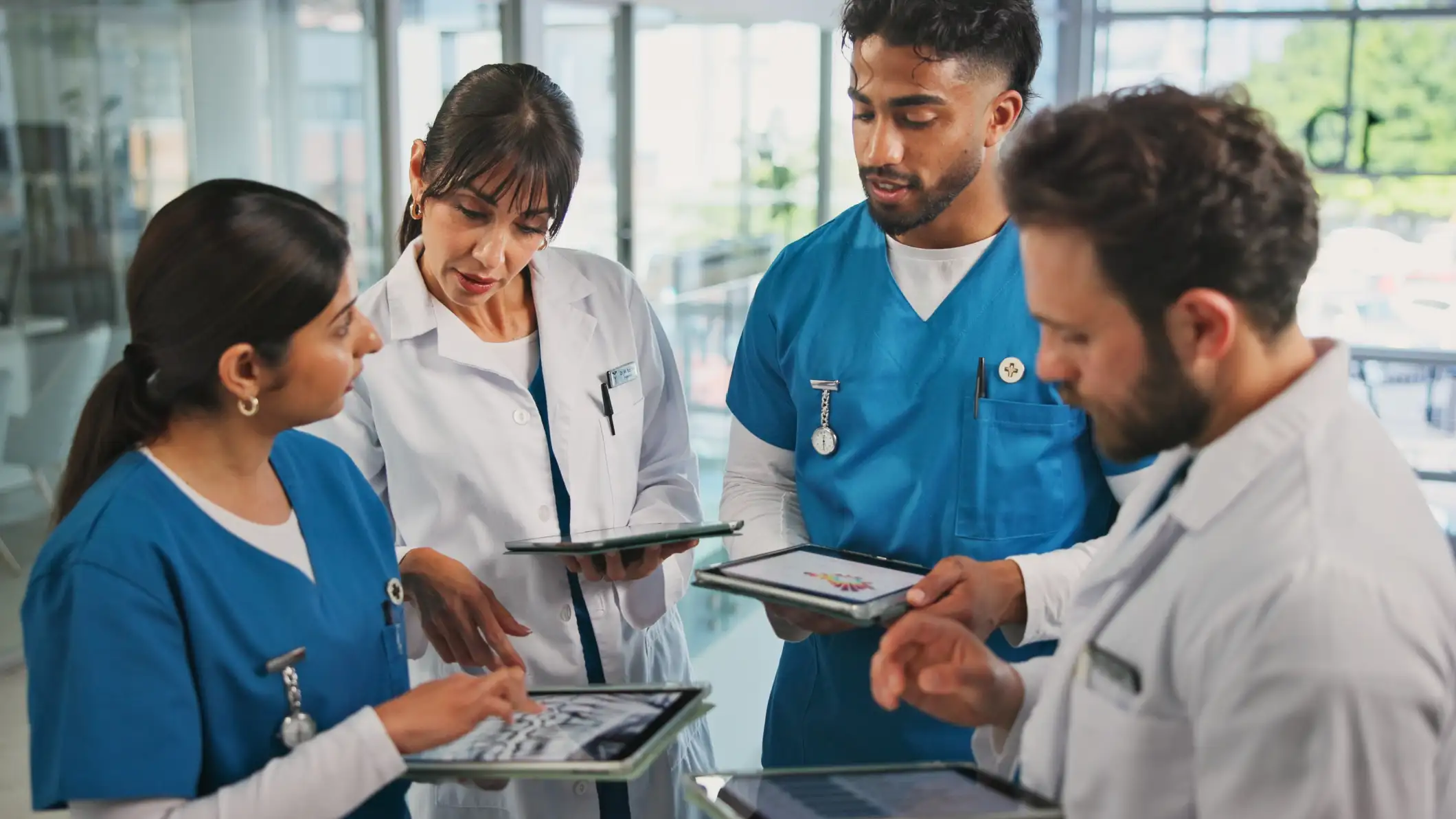 A group of doctors in a hospital looking at tablets and discussing information