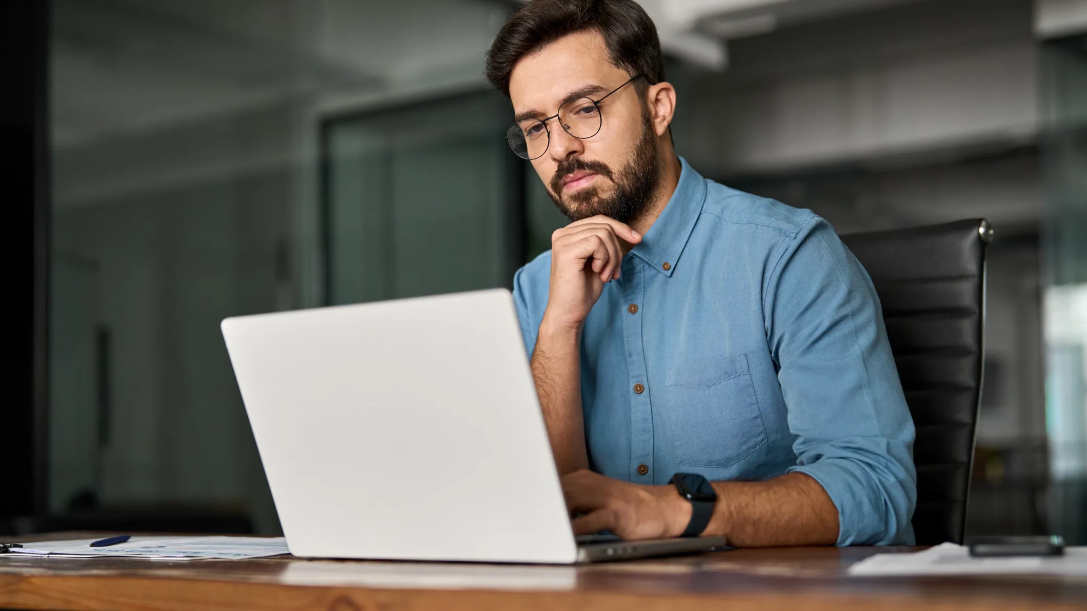 Young professional man in office looking intently at a laptop