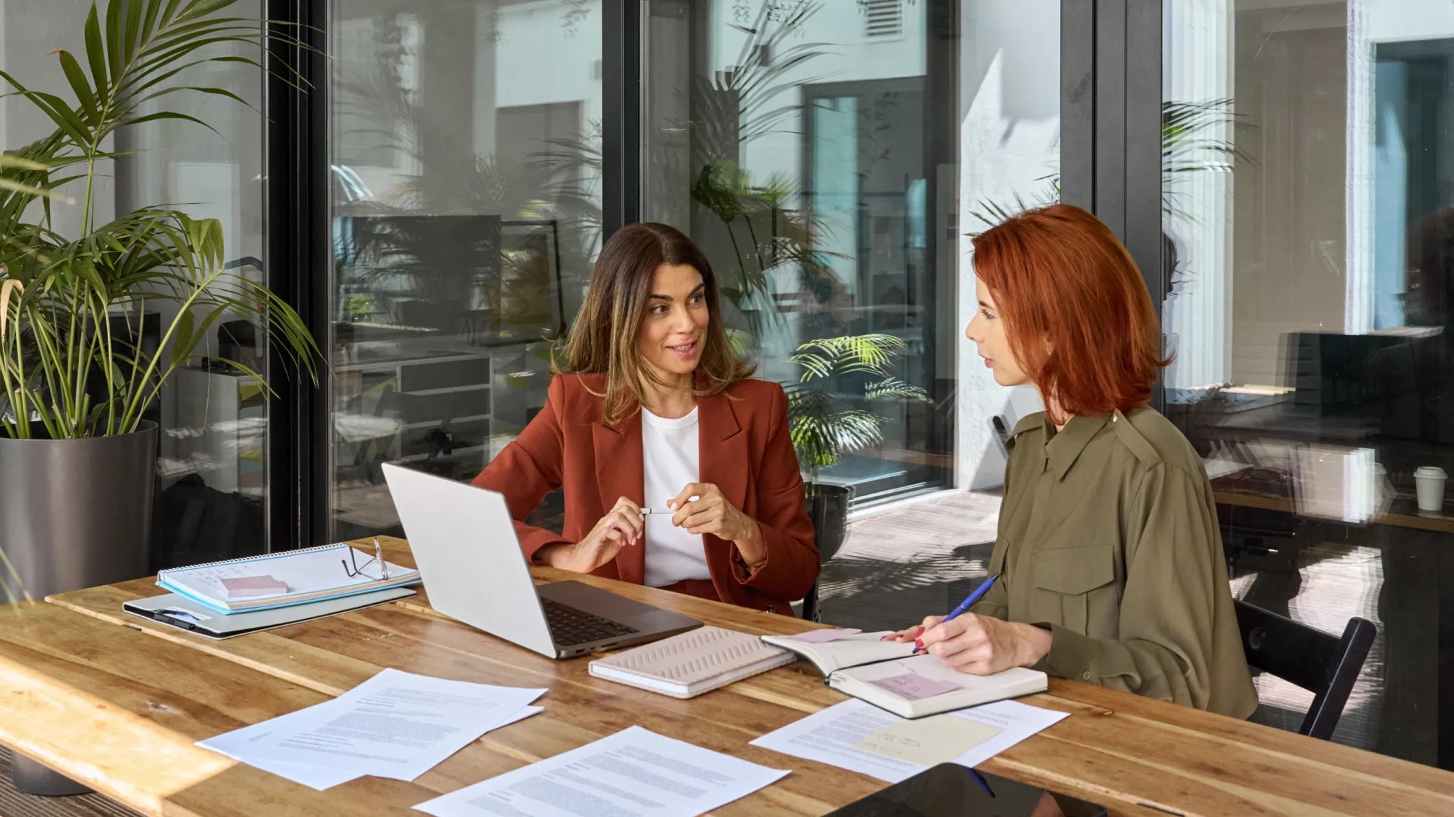 two business woman talking at a desk in a modern office