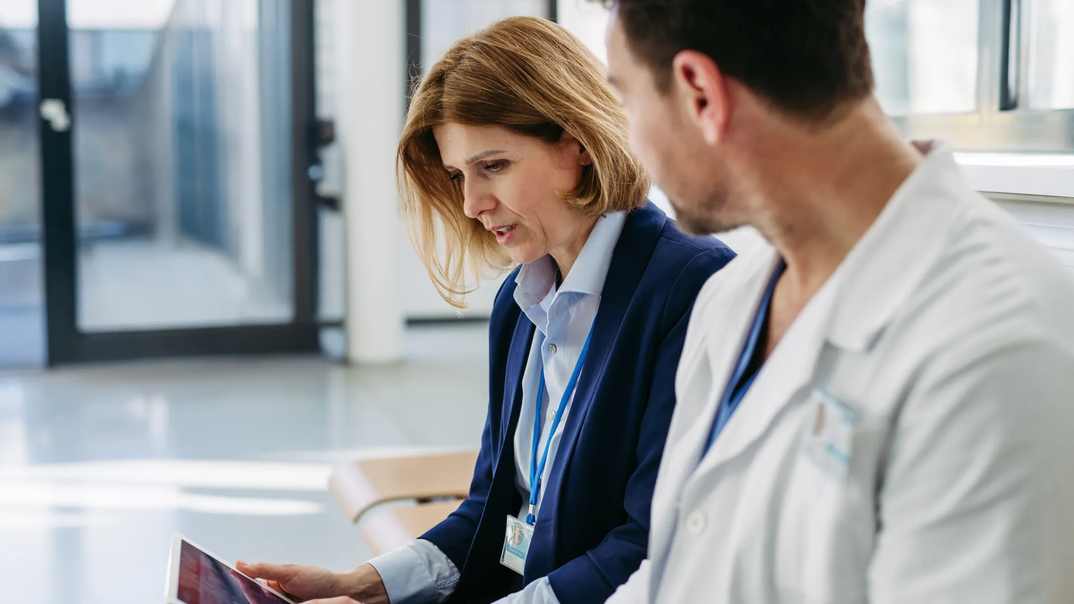 A female and male doctor discuss information on a tablet
