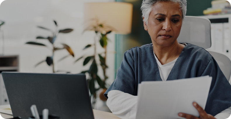 Healthcare professional at a laptop reviewing documents