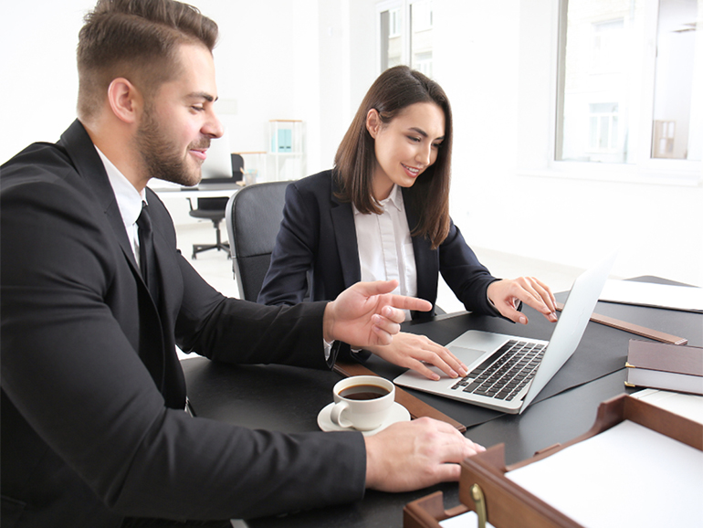 Two colleagues discussing in front of laptop screen