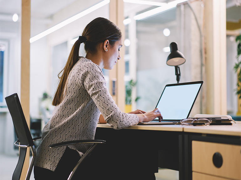 Female employee working at desk on laptop