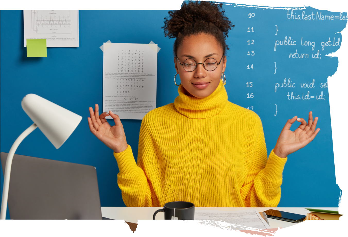 A woman in glasses meditating in front of a vibrant blue wall