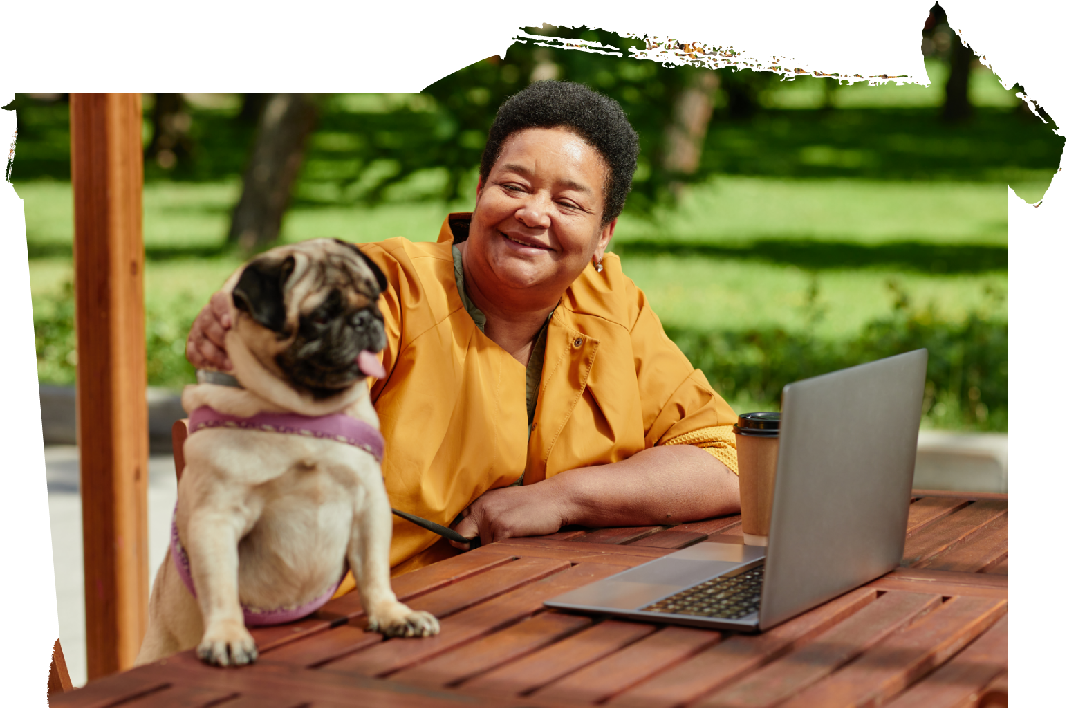 woman and pug dog in park with laptop