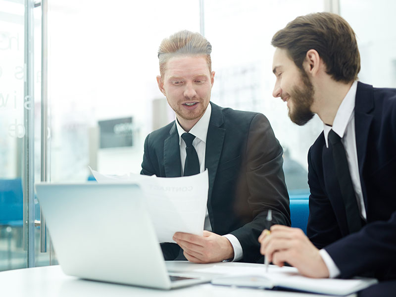 Two men in suits in office using our specialist solution to grow their business in the private sector