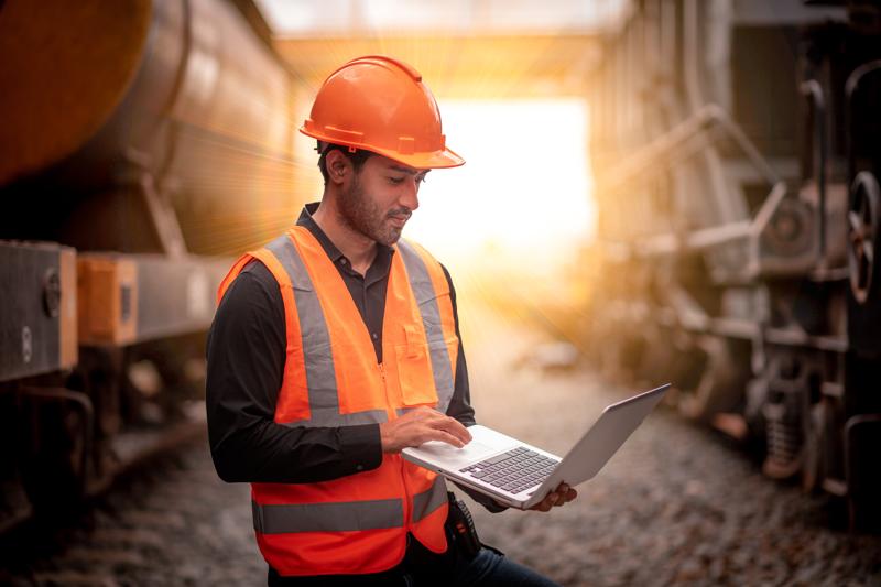 Engineer under inspection and checking construction process railway switch and checking work on railroad station by notebook .Engineer wearing safety uniform and safety helmet in work.